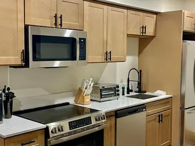a kitchen with stainless steel appliances and wooden cabinets at Luxury ADA Unit - 101 in Wilmington