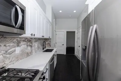 a kitchen with a stainless steel refrigerator and white cabinets at Chic & Modern - 30 Mins to NYC in Jersey City
