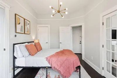 a white bedroom with a bed and a chandelier at Chic & Modern - 35 Mins to NYC - Extended Stays in Jersey City