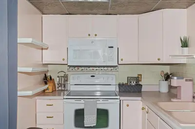 a kitchen with white cabinets and a stove and a microwave at Cozy meets fun! in Beacon