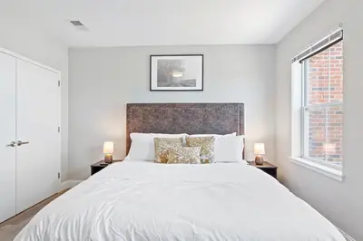 a white bedroom with a large bed with two lamps at Downtown NWK 1BR- Free Parking Easy NYC Access in Newark