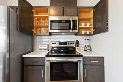 a kitchen with stainless steel appliances and wooden cabinets at Downtown NWK 1BR- Free Parking Easy NYC Access in Newark