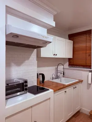a kitchen with white cabinets and a sink and a microwave at le plateau suite in Queens
