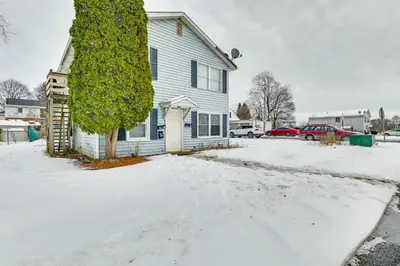 a white house with a tree in the snow at Near Hospitals Home with Yard in Albany! in Albany