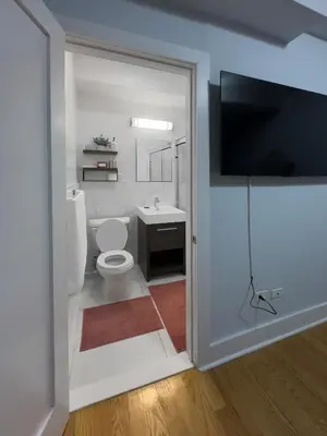 a bathroom with a toilet and a tv on the wall at Fordham University in University Heights