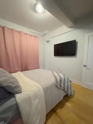 a bedroom with a bed and a flat screen tv at Fordham University in University Heights
