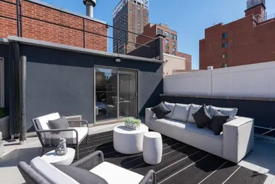 a patio with a couch and chairs on a building at 3BR Penthouse Suite with Massive Private Rooftop in New York