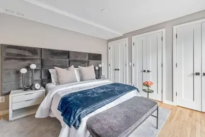 a white bedroom with a large bed with a bench at 3BR Penthouse Suite with Massive Private Rooftop in New York