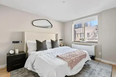 a bedroom with a large white bed and a window at 3BR Penthouse with Massive Private Rooftop in New York