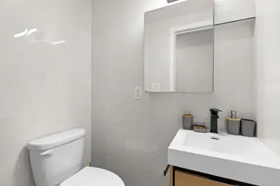 a white bathroom with a toilet and a sink at 105- 4BRs in the Heart of the East Village in New York
