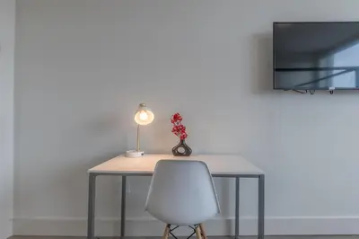 a table with a white chair and a lamp at Stylish Apt FREE Parking Near NYC & Airport in East Orange