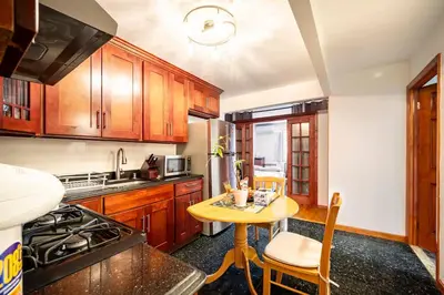 a kitchen with wooden cabinets and a small table at BEST LOCATION IN QUEENS, Everything is near by, PRIVATE ROOM, LaGuardia Airport 10min in Queens