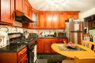 a kitchen with wooden cabinets and a wooden table with a tableablish at BEST Large Private Room & Private Bathroom, LaGuardia Airport 10min in Queens