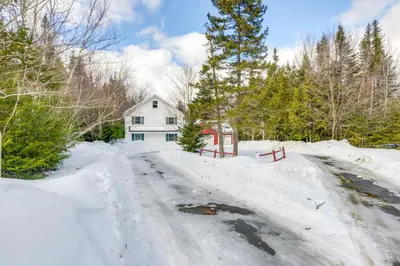 a snow covered road in front of a white house at Ski, Golf and Hike Spacious Dover Retreat! in Dover