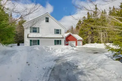 a white house with a red barn in the snow at Ski, Golf and Hike Spacious Dover Retreat! in Dover