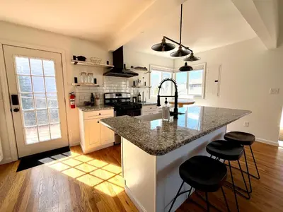 a kitchen with a granite counter top and stools at Peak to Lake Escape in Greenwood Lake