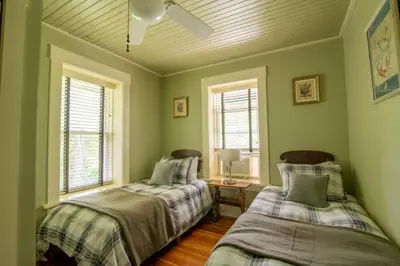 two beds in a room with green walls and windows at Antrim Streamside in Livingston Manor