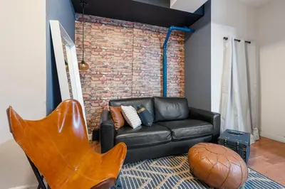 a living room with a leather couch and a brick wall at 4 Bedroom 1 Bathroom Hudson Yard in New York