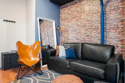 a living room with a leather couch and a brick wall at 4 Bedroom 1 Bathroom Hudson Yard in New York