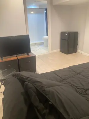 a bedroom with a bed and a television and a bathroom at Cozy bedroom with en-suite bathroom in Naugatuck