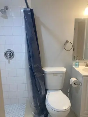 a bathroom with a toilet and a blue shower curtain at Cozy bedroom with en-suite bathroom in Naugatuck