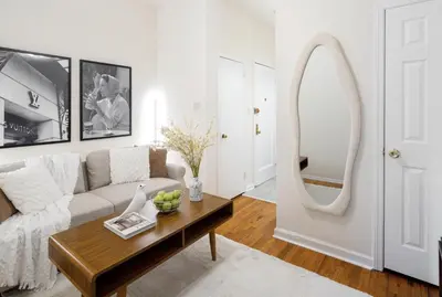 a living room with a couch and a mirror at Cozy Apartment in the Upper East Side in New York