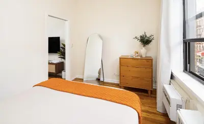 a bedroom with a bed and a dresser and a mirror at Cozy Apartment in the Upper East Side in New York