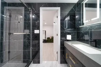 a bathroom with a sink and a shower with black tiles at Upscale 4BR Retreat at the Reservoir! in Bridgeport