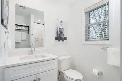 a white bathroom with a toilet and a sink at Upscale 4BR Retreat at the Reservoir! in Bridgeport