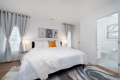 a white bedroom with a large white bed with orange pillows at Upscale 4BR Retreat at the Reservoir! in Bridgeport