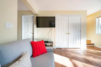 a living room with a gray couch and a red pillow at Lovely 3BR Homewith free parking-WALK to WP Gate in Highland Falls