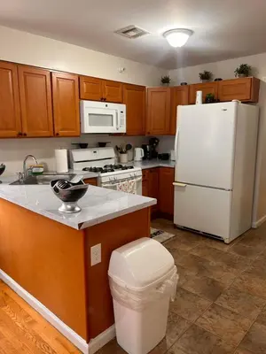 a kitchen with a white refrigerator and wooden cabinets at Elegant 3BR Home - Near the Prudential Center in Newark