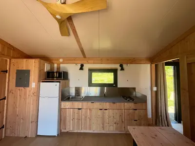 a kitchen with a white refrigerator and wooden cabinets at Huttopia Berkshires in Hancock