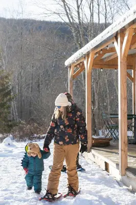 a woman and a child standing in the snow at Huttopia Berkshires in Hancock