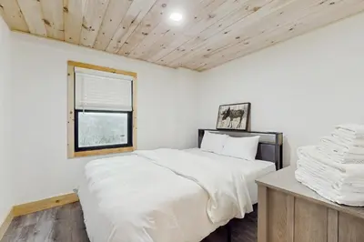 a white bedroom with a bed and a window at Timber Riverhouse in Readsboro