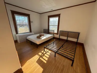a room with a bed and a bench and two windows at Warm and Cozy 4Bd 2Bath in Southington