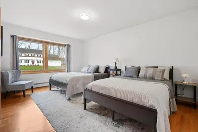 a bedroom with two beds and a chair and a window at 40 Spacious Sleek Cozy in Middletown