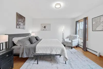 a white bedroom with a bed and a chair at 40 Spacious Sleek Cozy in Middletown