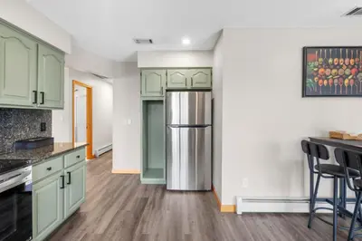 a kitchen with green cabinets and a stainless steel refrigerator at 40 Spacious Sleek Cozy in Middletown
