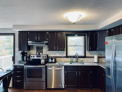 a kitchen with black cabinets and stainless steel appliances at 16 A COZY GETAWAY 4BED 3BATH HOME W FIRE PIT in Southington
