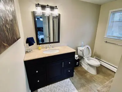 a bathroom with a sink and a toilet and a mirror at 16 A COZY GETAWAY 4BED 3BATH HOME W FIRE PIT in Southington
