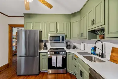 a kitchen with green cabinets and a stainless steel refrigerator at 25 Massive 5 BR in Downtown Southington in Southington