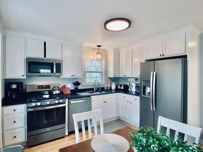 a kitchen with white cabinets and a black refrigerator at 23 COMFORT AND LUXURY 3 BR 2 BA House in Southington