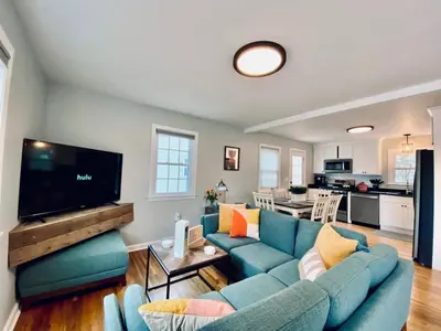 a living room with a blue couch and a flat screen tv at 23 COMFORT AND LUXURY 3 BR 2 BA House in Southington