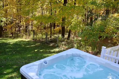 a jacuzzi tub in a yard next to a forest at Beautifully Designed 4BR Home Heated Pool HotTub in Valatie