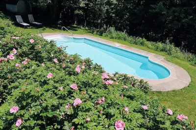 a swimming pool in a garden with pink flowers at Beautifully Designed 4BR Home Heated Pool HotTub in Valatie