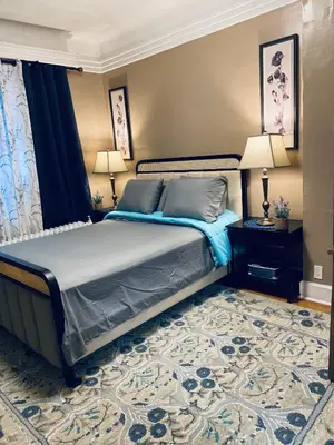 a bedroom with a bed and two lamps and a rug at NYC cozy room in Van Nest