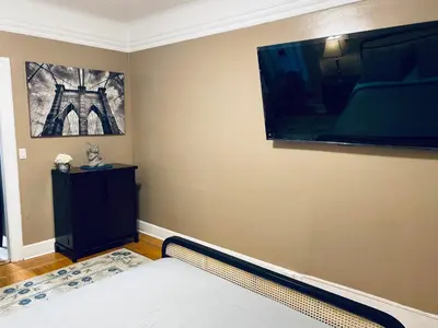 a bedroom with a bed and a large tv on the wall at NYC cozy room in Van Nest