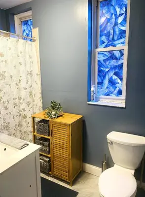 a bathroom with a toilet and a blue wall at NYC cozy room in Van Nest