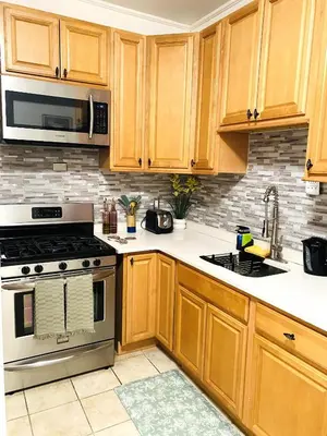 a kitchen with wooden cabinets and a stove and microwave at NYC cozy room in Van Nest